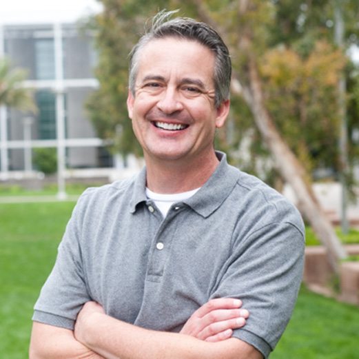 man smiling with arms crossed while standing outside