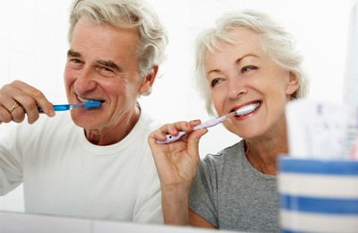 older couple brushing teeth in bathroom