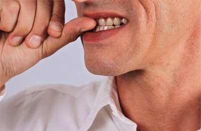 closeup of man biting fingernails 