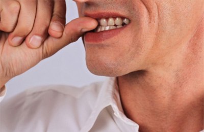 closeup of man biting fingernails