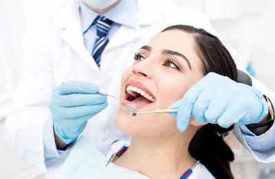 patient sitting while dentist looks in mouth 