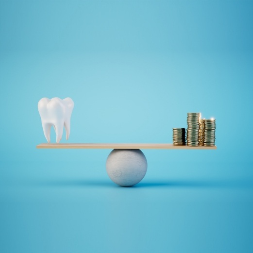 Scale with model of tooth on one side and pile of coins on the other