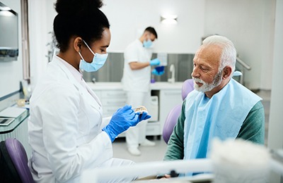 Older man learning about dentures at the dentist’s office