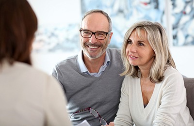 Couple smiling while talking to dentist during appointment