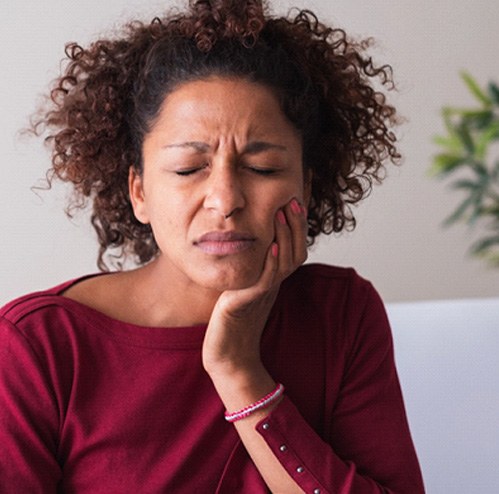 Woman with toothache sitting on couch at home