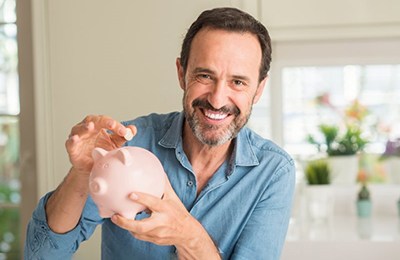 a man holding a piggy bank for dental implants