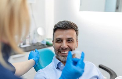 a dentist showing a patient how to wear Invisalign aligners