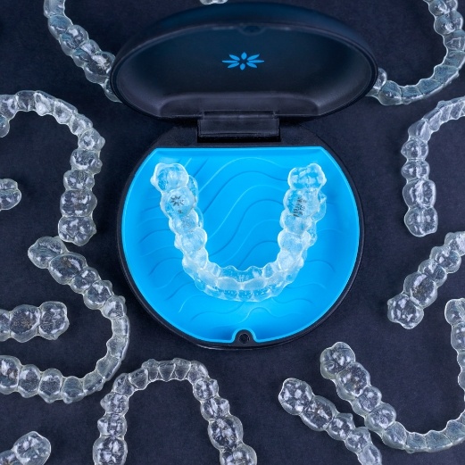 Invisalign tray in carrying case surrounding by many other Invisalign aligners in Schoharie