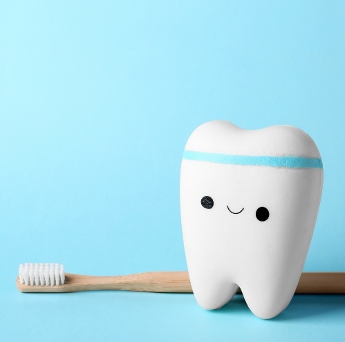 Animated tooth wearing a sweatband next to a wooden toothbrush