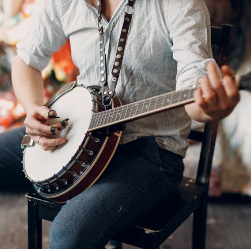 Person sitting in a chair and playing the banjo
