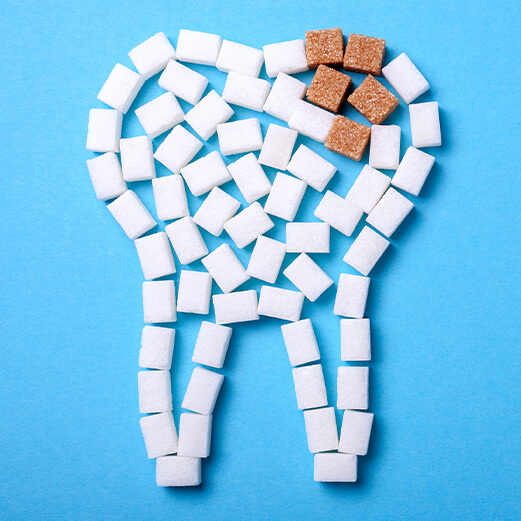 White sugar cubes forming the shape of tooth with some brown sugar cubes representing cavity