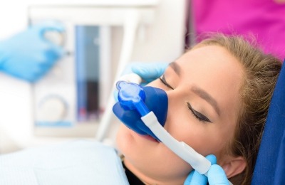 Young woman wearing nitrous oxide sedation mask in dental chair