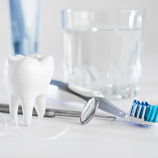 Dental instruments laying on table with glass of water toothbrush and model of tooth