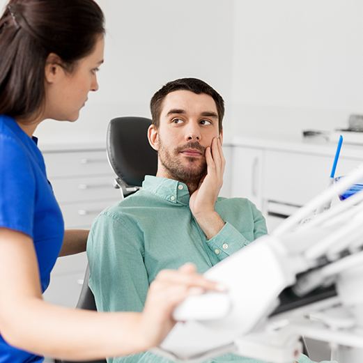 Male patient with failed dental implant talking to assistant